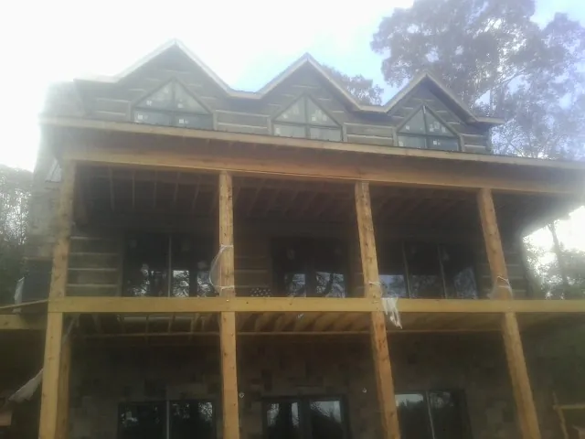 Dormers and porch framing on a large log home under construction — Roof Coating work by our crew in Bellefontaine