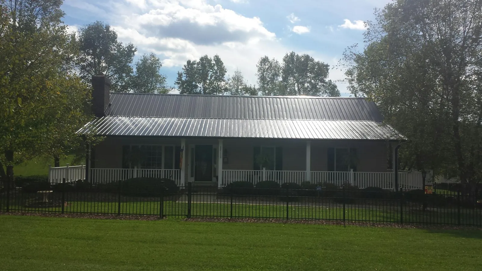 Gray metal roof on a brick ranch with a full width front porch — Gutter Guard Installation work by our crew in Bellefontaine