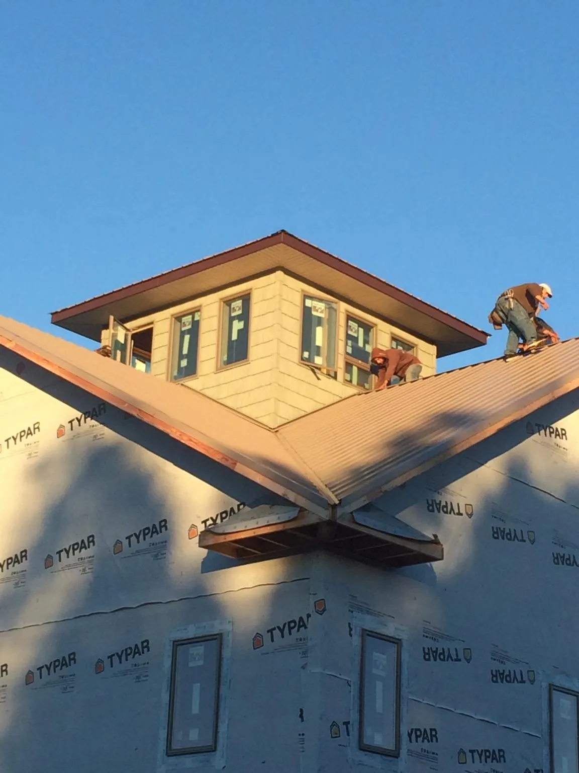 Roofers working around a rooftop cupola on a new metal roof at sunset — Roof Waterproofing in Bellefontaine by Roofing Brothers